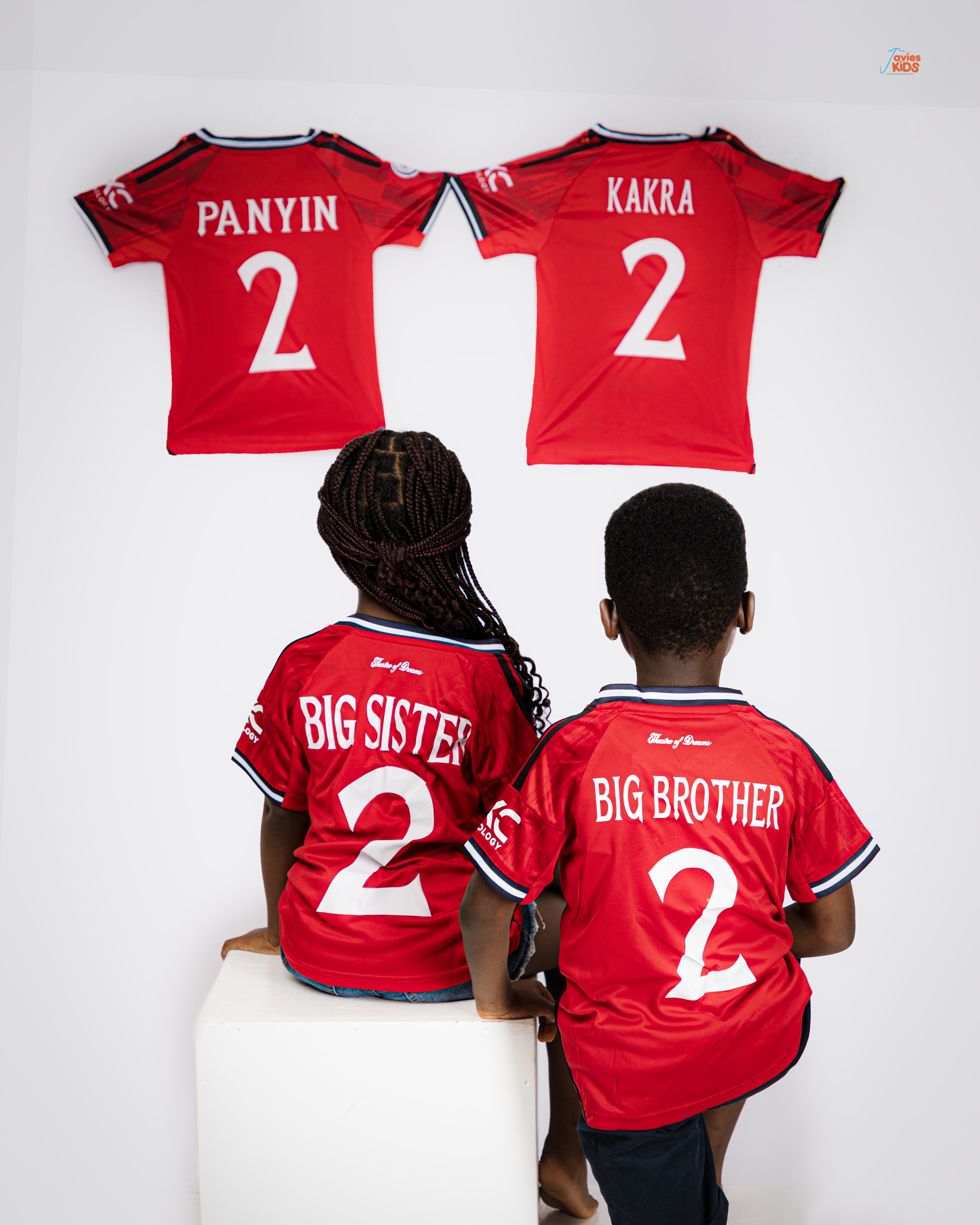 Brother and sister in matching red kits by Javies Photography Studio